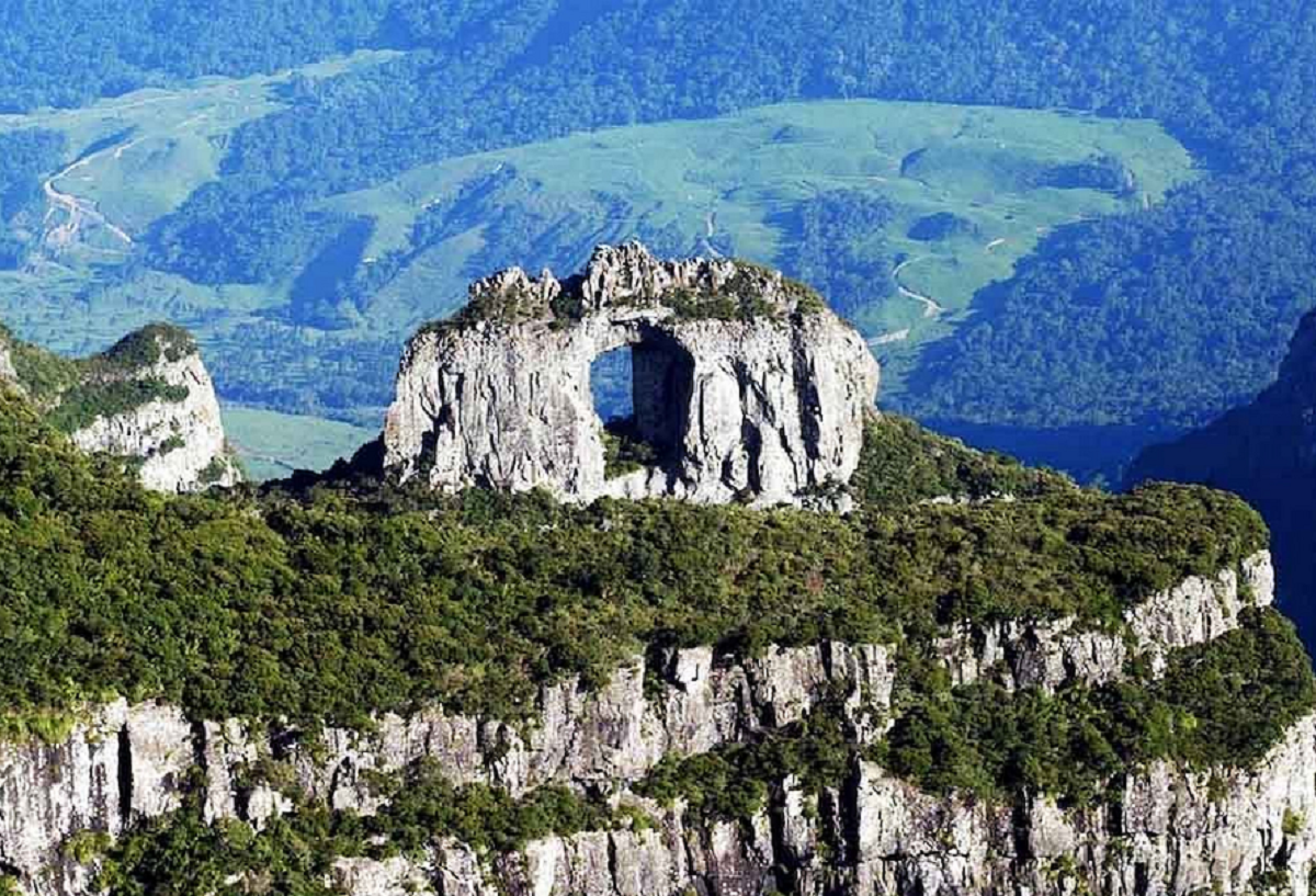 Vista panorâmica da Pedra Furada em Jericoacoara, com o arco rochoso sobre o mar e a paisagem costeira ao redor